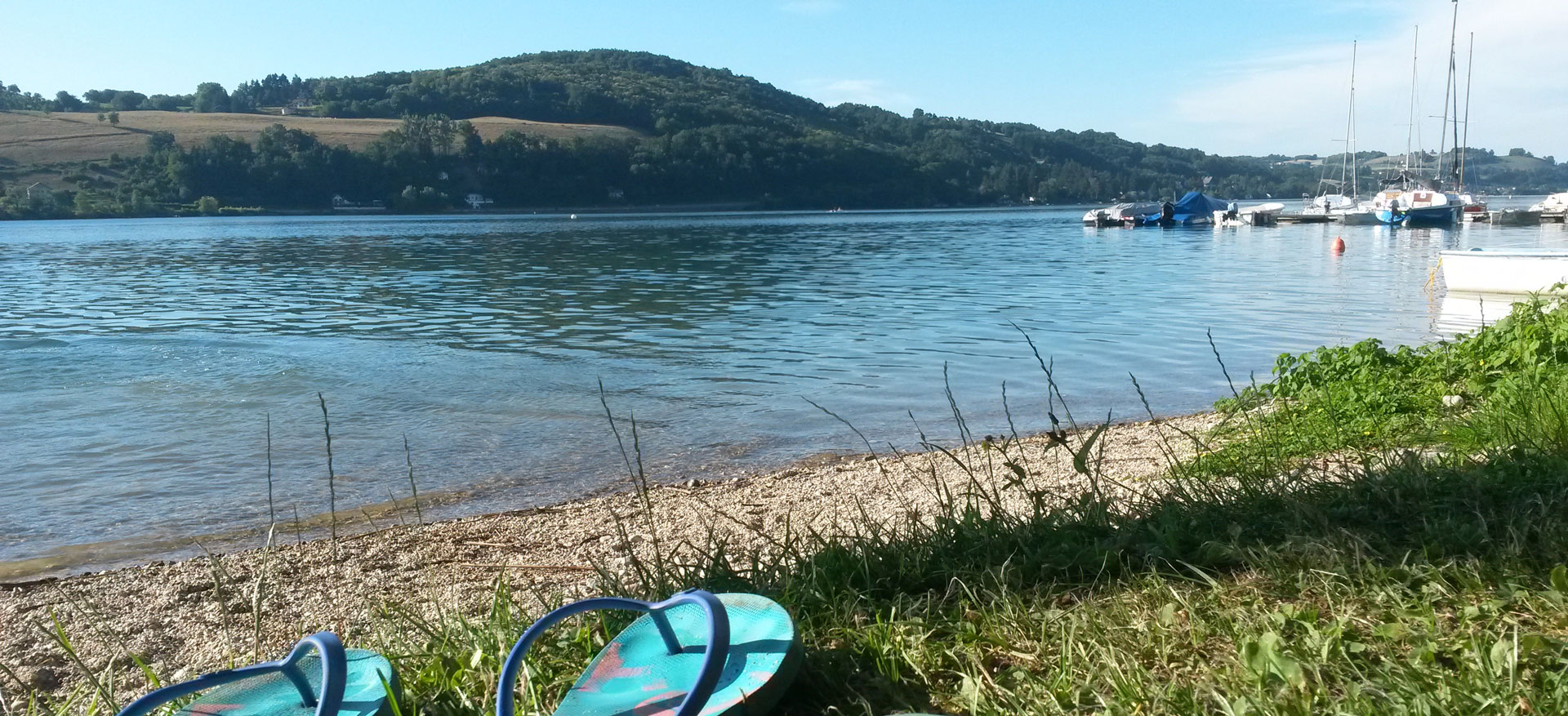 Vue sur l'eau et le ponton à bateau depuis le bord du lac, le camping de Bilieu.