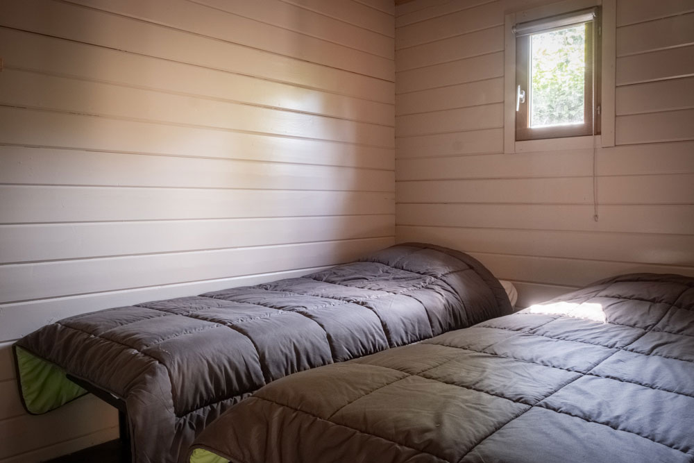 Location de chalets en bois. Vue intérieure. La chambre avec deux lits simples.