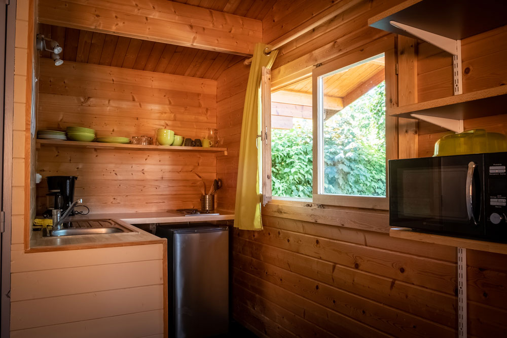 Location de chalets en bois. Vue intérieure. La cuisine avec un évier, un réfrigérateur, une plaque de cuisson et un four.