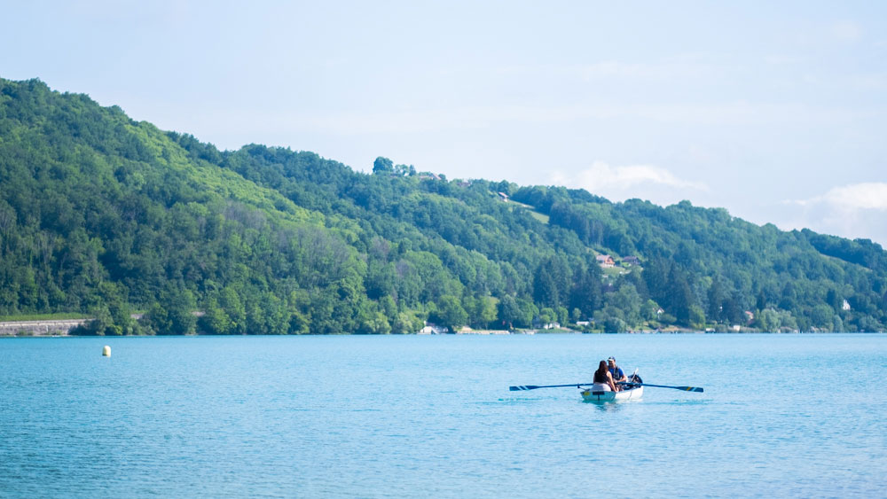 Vue depuis la plage du lac de Paladru et des collines environnantes. Promenade en barque sur l'eau.